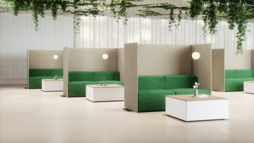 Modern office lounge with green sofas, partition walls, and hanging plants. White tables with small plants adorn the space