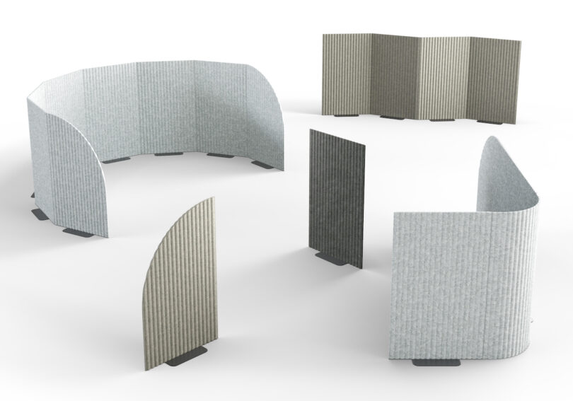A group of freestanding, curved, and flat acoustic panels in various shades of gray are arranged on a white surface