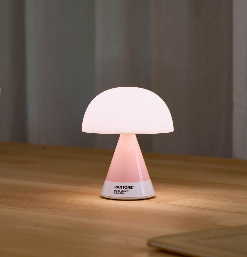 A small, mushroom-shaped table lamp with a pink base and white dome shade, labeled 