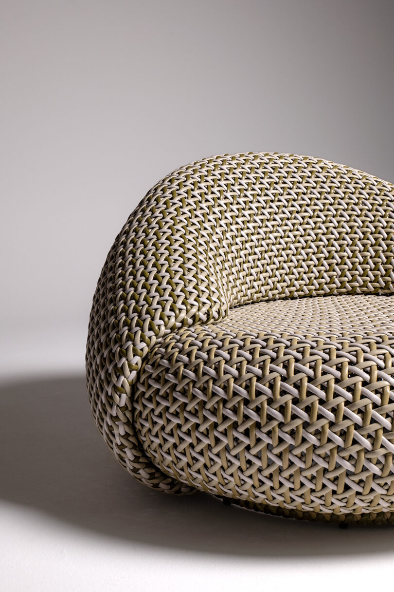 Detail of a modern woven chair set against a plain white background.