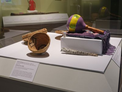 A vitrine holds a basket and a maraca-like instrument. 