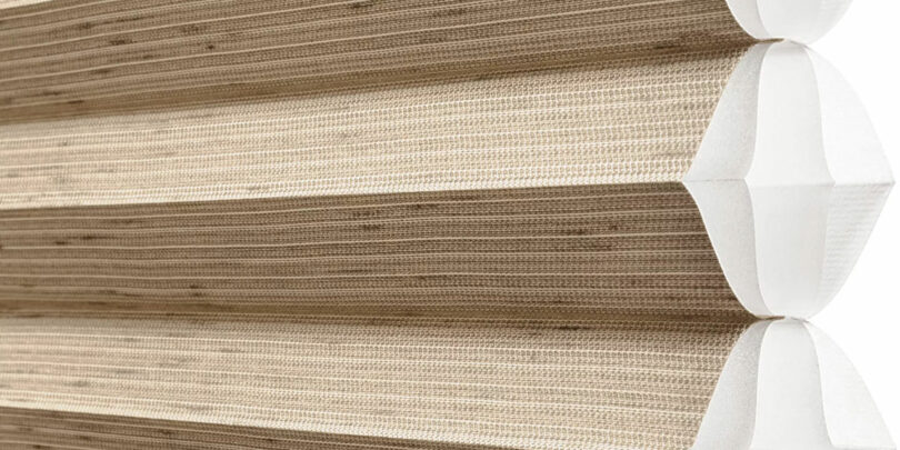 Close-up of a beige pleated cellular shade with a honeycomb structure.