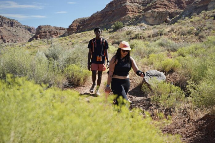 Two people walk through the desert while wearing hiking shoes