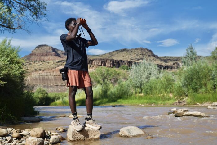 A man looks through binoculars while wearing hiking boots