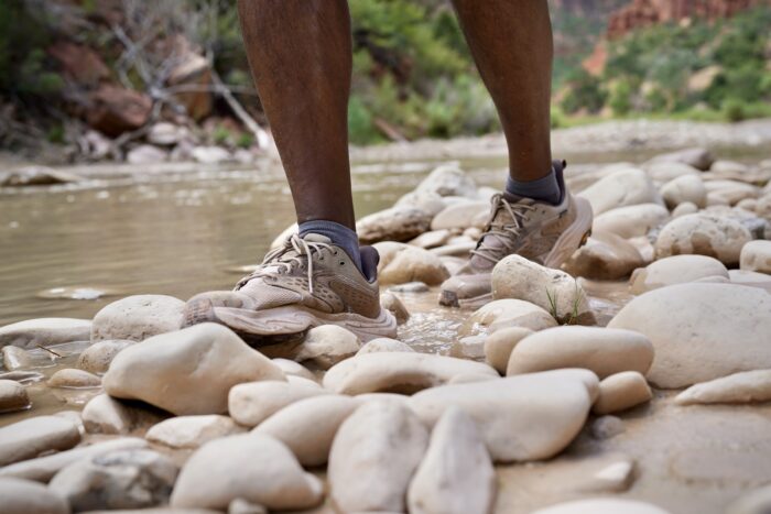 A man walks by a river with hiking shoes