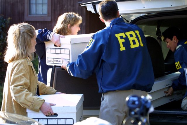 Three people putting boxes into the back of a car.
