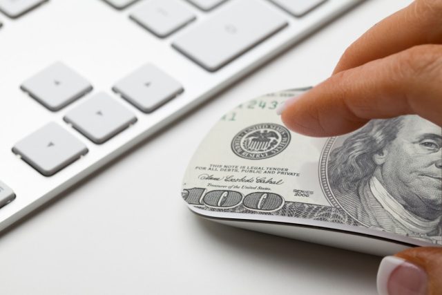 Commercetools-a-pioneer-in-headless-commerce-lays-off-dozens-of.jpg Hand on mouse with 100 dollar bill design on it.