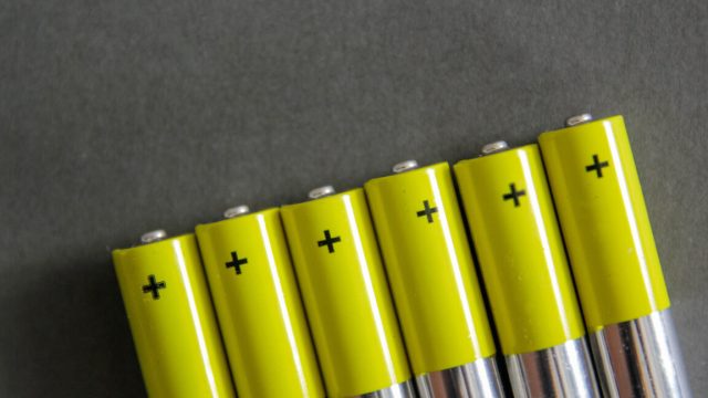 A row of AA batteries, with the positive pole colored in green and labeled with a plus sign.