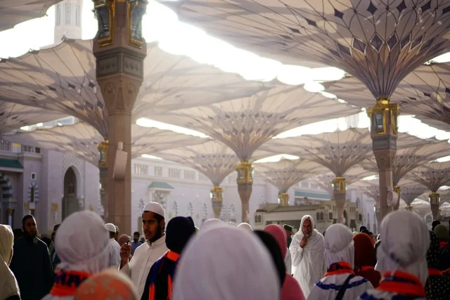 Saudi-Hits-Record-Arrivals-Needs-Faster-Pace-to-Reach-70.jpg People walking under shading umbrella structures in Medina, Saudi Arabia