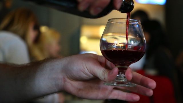 Scientists-found-a-faster-way-to-brew-sour-beer—with-peas.jpg hand holding glass while other hand pours sour beer into it