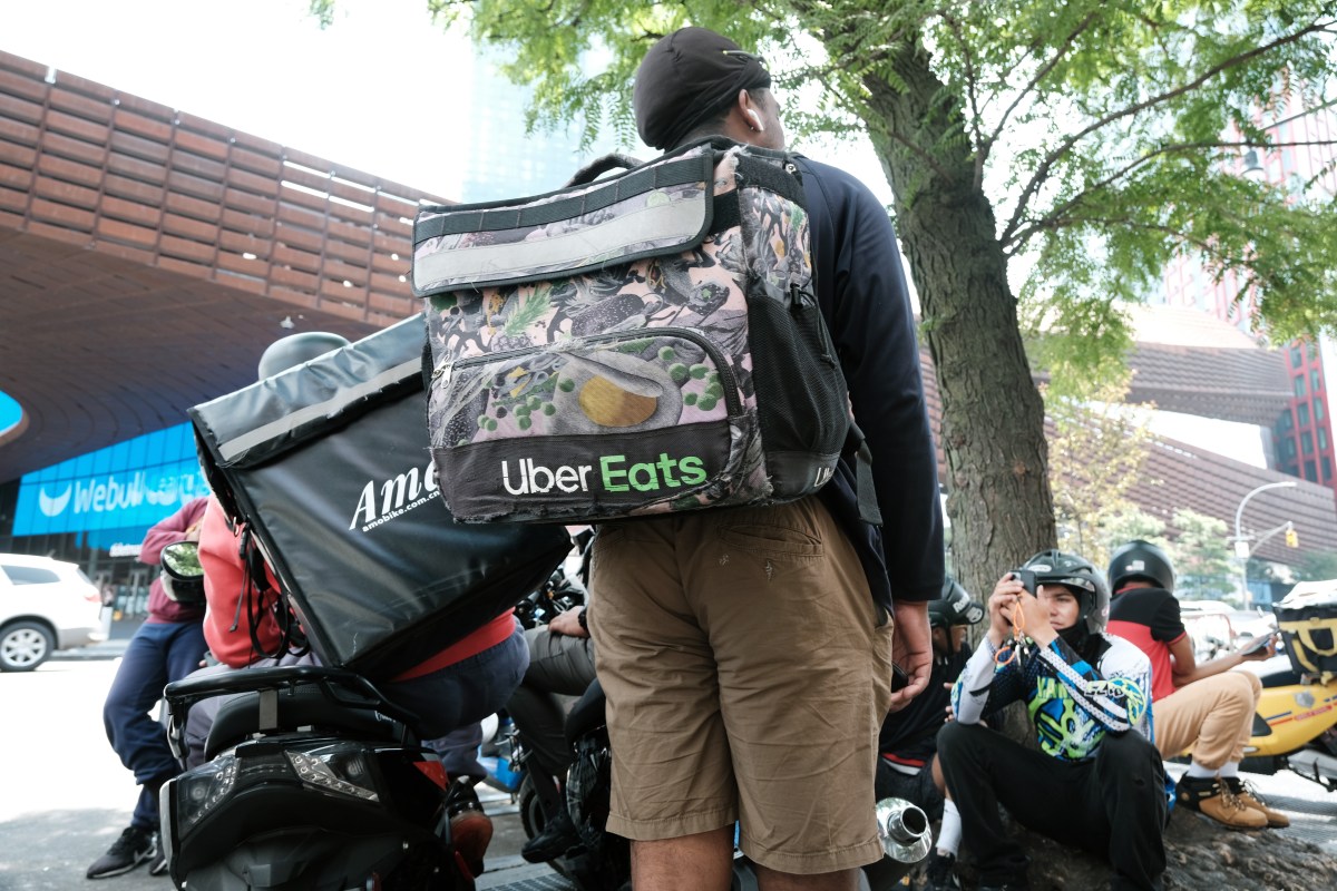Uber-sues-DoorDash-alleging-anti-competitive-tactics.jpg App-based delivery workers wait outside of a restaurant that uses app deliveries