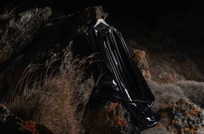 A hanger holding a black, rubbery garment. The hanger is hung from a rock.