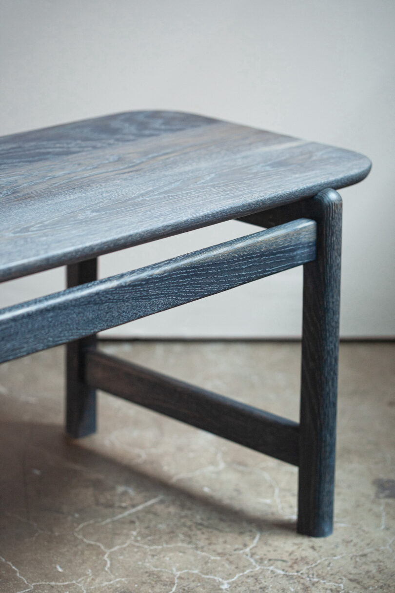 A dark wooden table with a rectangular surface and angled legs on a stone floor