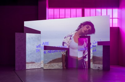 A video showing a person swaying. The video is projected in a purple-toned room and split across multiple walls.