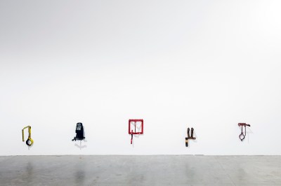 A group of sculptures composed of metal contraptions affixed to a wall.
