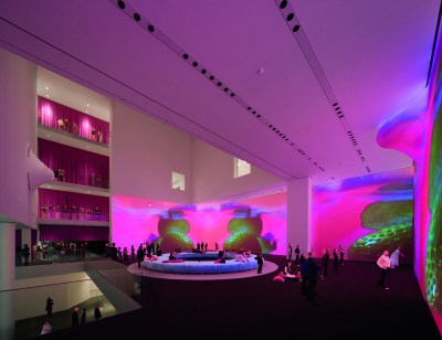 An atrium whose tall walls are projected with abstract pink imagery.