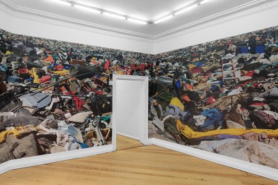A photograph of trash that spans multiple walls with a doorway cut out.