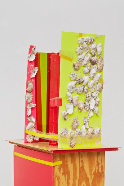 A sculpture formed from colored cardboard affixed with seashells.