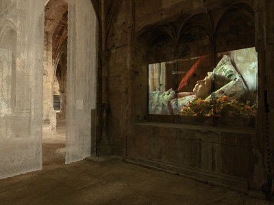 A projection showing a dead woman lying in bed.
