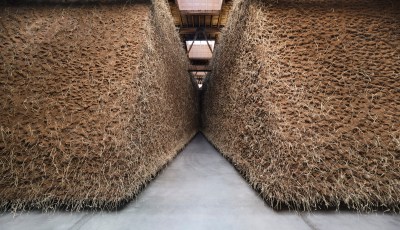 Two tall mounts of hay, dirt, coir, and more with an aperture between the.