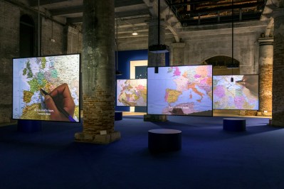 Several hanging screens showing a hands running markers along maps.