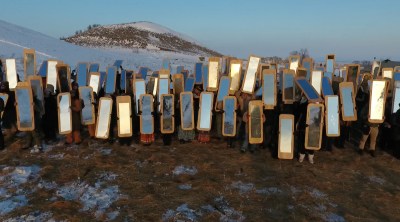 A group of people holding mirrors in front of them in a snowy, mountainous landscape.
