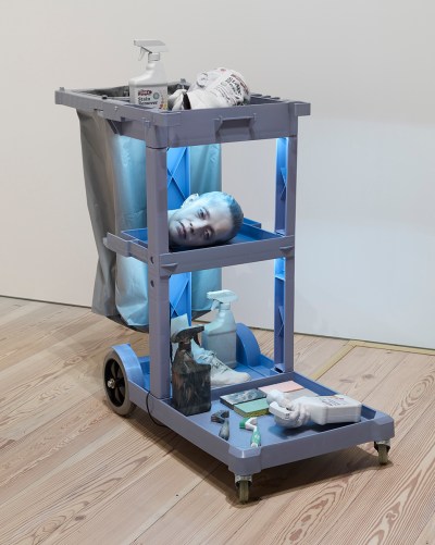 A custodian's pushcart with 3D printed cleaning products, a head, and more in it.