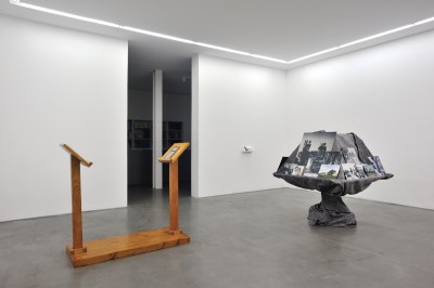 A gallery with two sculptures. One resembles two podia on a wooden platform.