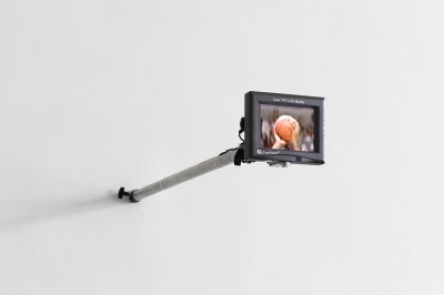A small screen extending from a wall that shows two hands gripping a basketball.
