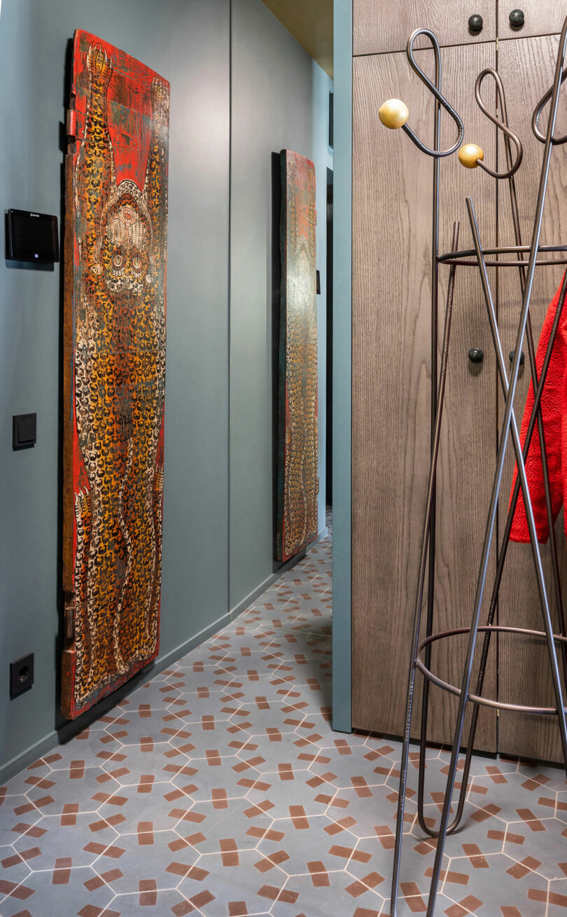 Hallway with a decorative door on the left, patterned floor tiles, and coat rack on the right.