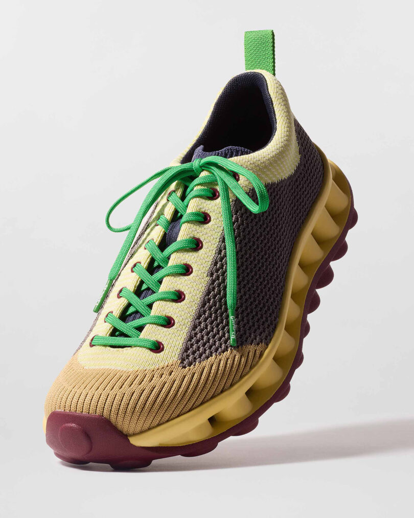 A multicolored sneaker with green laces, a yellow and purple mesh upper, and a distinctive thick, grooved sole.