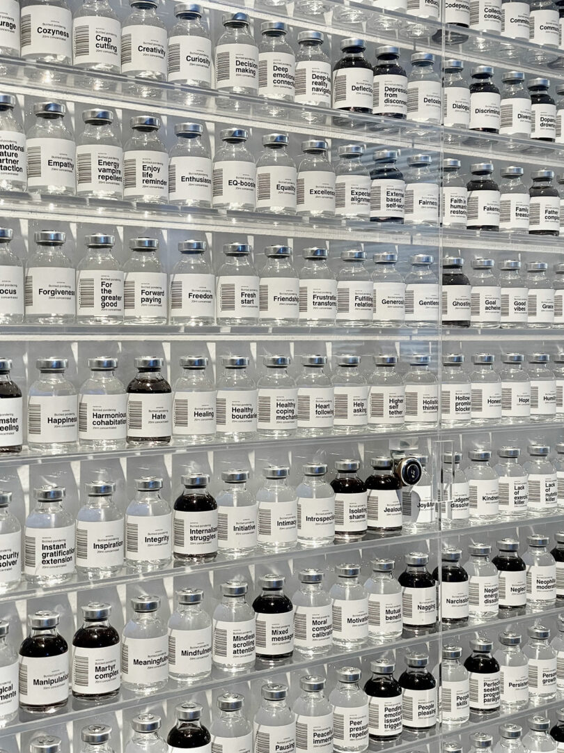A wall with shelves of glass jars, each labeled with different emotions and concepts, arranged in alphabetical order.