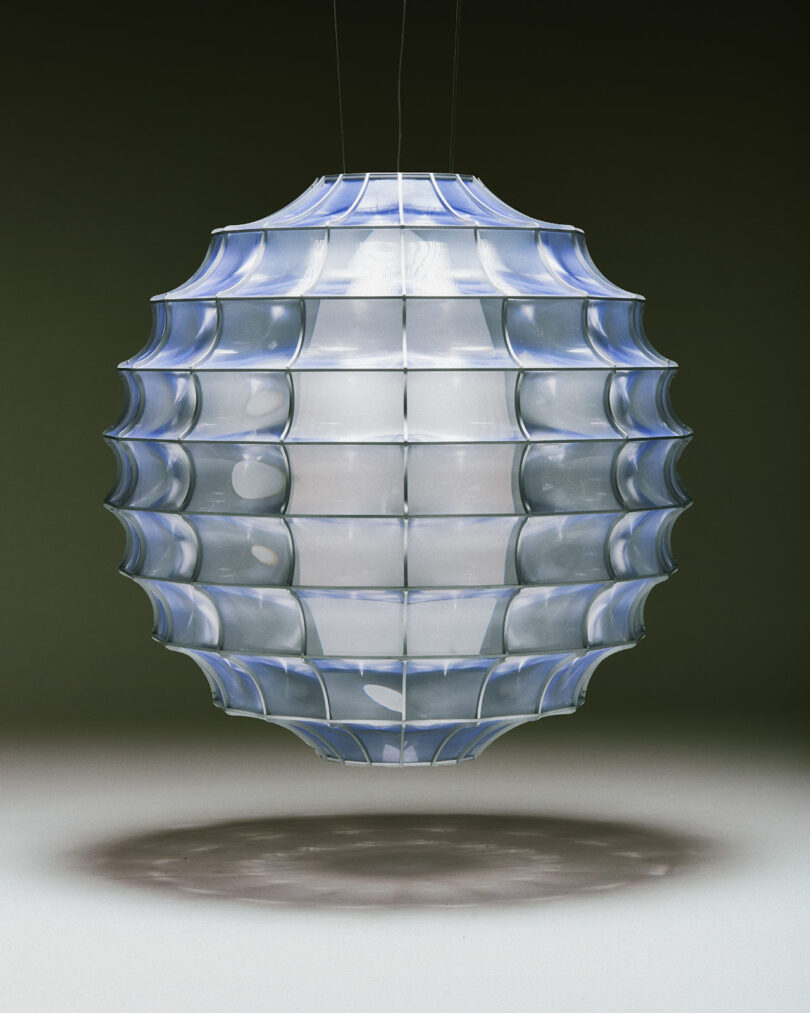 Futuristic hanging lamp with a geometric, segmented design and a translucent glow, casting a shadow below.