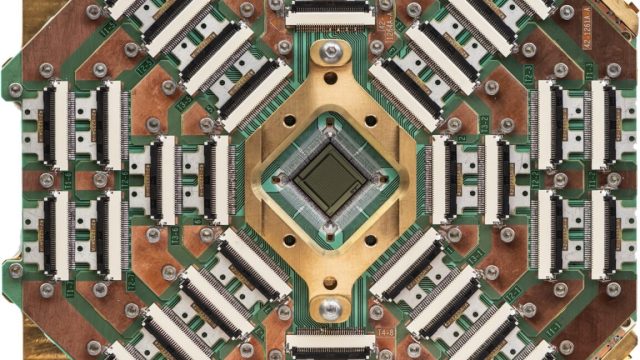 D-Wave-quantum-annealers-solve-problems-classical-algorithms-struggle-with.jpeg Image of a complex pattern of circuitry and connections, primarily golden in color, surrounding a black square chip in the center.