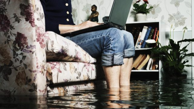 Open-Source-devs-say-AI-crawlers-dominate-traffic-forcing-blocks.jpg man sitting in sofa in a flooded living room, feets in water, writing on a laptop