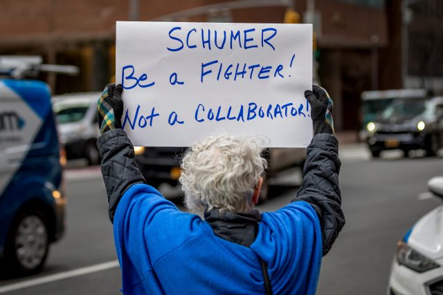 Schumer-Says-Hes-Not-Stepping-Down-and-Criticizes-Trump.jpeg An activist participates in a protest outside the office of