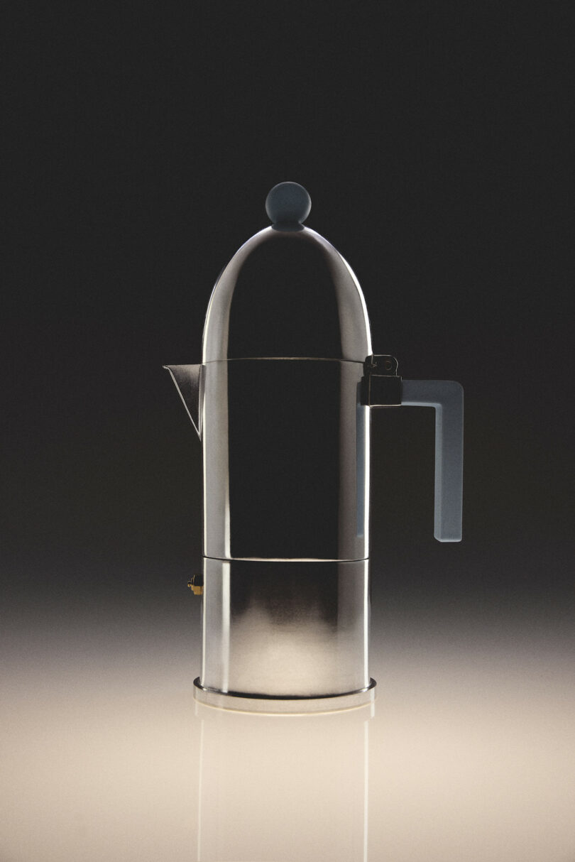 A stainless steel stovetop coffee maker with a blue handle and knob is centered against a dark gradient background, reflecting light on the glossy surface below