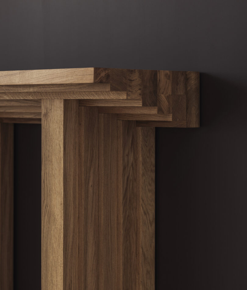 Close-up of a wooden table with interlocking joints against a dark background, showcasing detailed craftsmanship and texture