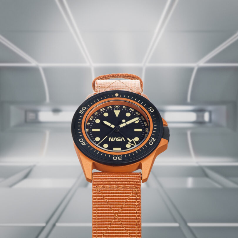 A person wearing a wristwatch with an orange strap and black dial, displaying the time on their left wrist.