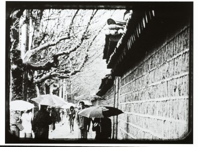 A film still showing people holding umbrellas on a snowy day next to a palace wall in Korea. 