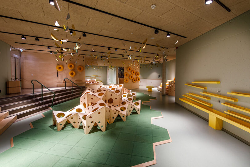 Modern interior with abstract geometric structures and hanging decorations, featuring a green and yellow color scheme.