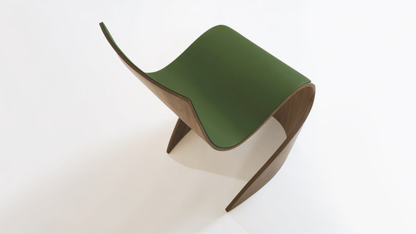 Curved, modern chair with a green seat and wooden base, set against a plain white background