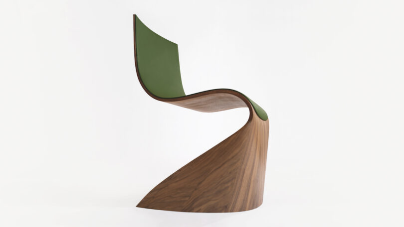 Curved, modern chair with a green seat and wooden base, set against a plain white background