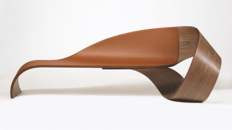 Modern, curved wooden bench with an integrated seat, featuring a smooth, flowing design and a mix of wood and brown material