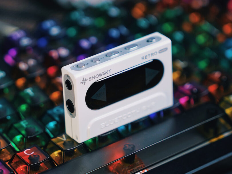 A white Snowisy Retro audio device with buttons is placed on a colorful backlit keyboard.