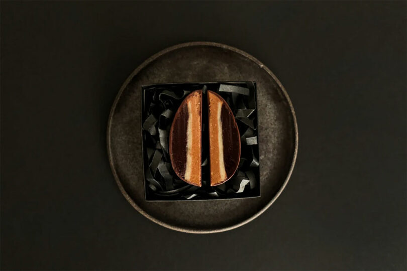 A sliced chocolate-covered confectionery is displayed on a textured plate against a dark background.