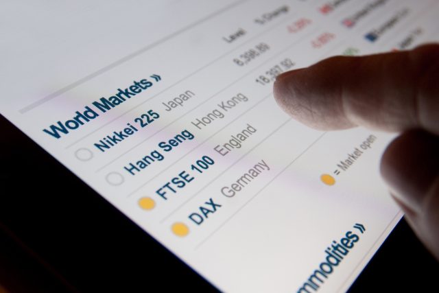 1744978085_Which-Travel-Stocks-are-Sinking-Most-on-Monday.jpeg A finger hovering over a screen listing world markets.
