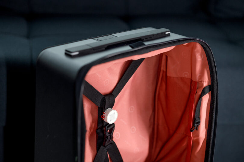 Open suitcase with a pink interior, black straps, and a partially visible handle.