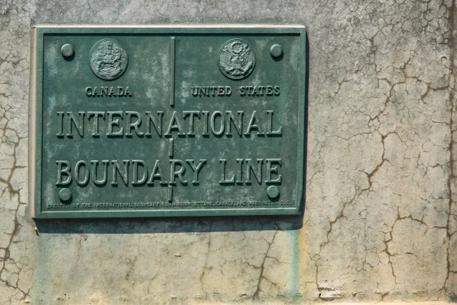Canada-Warns-Citizens-of-US-Border-Device-Searches.jpeg Brass plaque between New York State and Ontario.