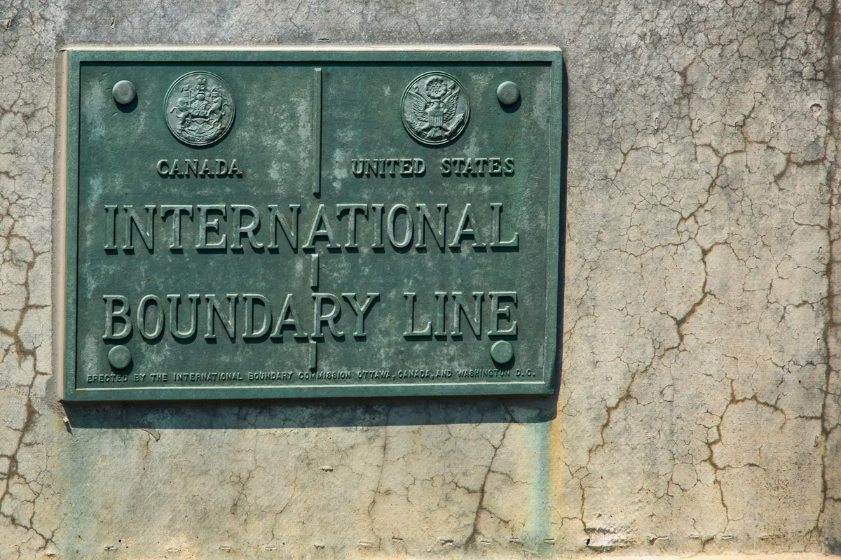 Canada-Warns-Citizens-of-US-Border-Device-Searches.jpeg Brass plaque between New York State and Ontario.